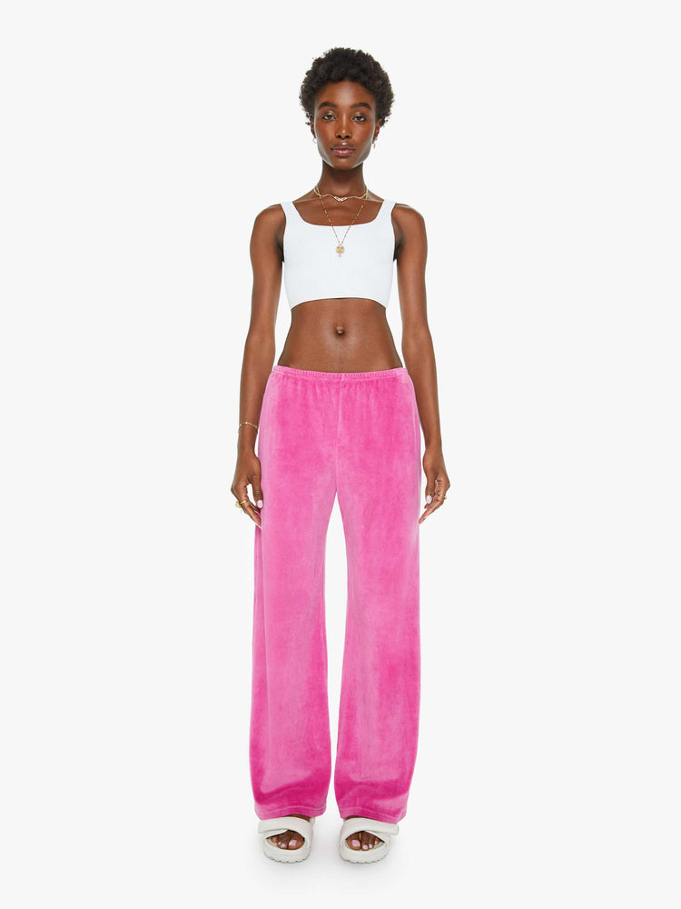 Front view of a woman in a pink velour sweatpants with an elastic waistband, side slit pockets, a wide straight leg and a loose fit.