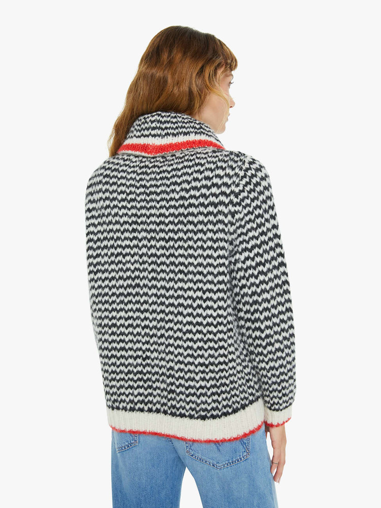 Back view of a woman in a black and cream stripes with red trim sweater with a shawl collar, deep V-neck, slit pockets, ribbed hems and a slightly oversized fit.