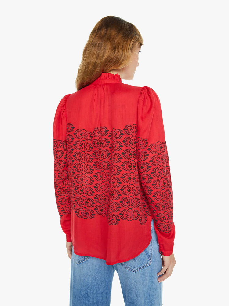 Back view of a woman blouse in red with black printed details, and features a ruffled collar, puffed shoulders, buttons down the front and a slightly cropped fit.