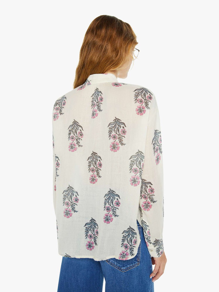 Back view of a woman blouse in cream with a grey and pink floral print, and features a stacked collar, buttoned V-neck, long sleeves and a loose fit.