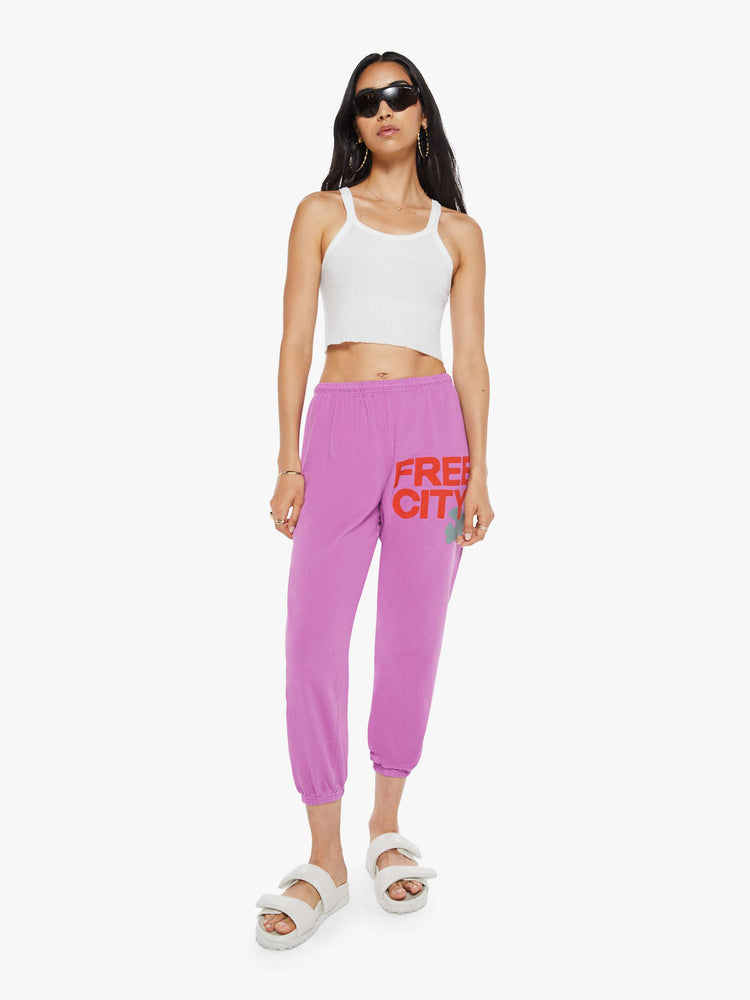 Front view of a woman in pink sweatpants are designed with a drawstring waistband, elastic hems, a loose, wide leg and the brand's logo in red at the hip.