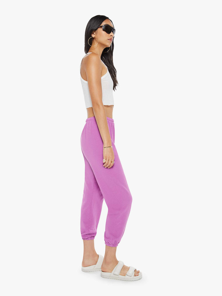 Side view of a woman in pink sweatpants are designed with a drawstring waistband, elastic hems, a loose, wide leg and the brand's logo in red at the hip.