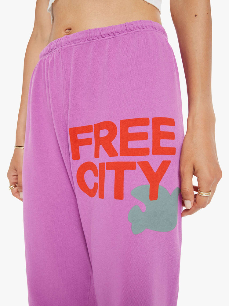 Close up view of a woman in pink sweatpants are designed with a drawstring waistband, elastic hems, a loose, wide leg and the brand's logo in red at the hip.