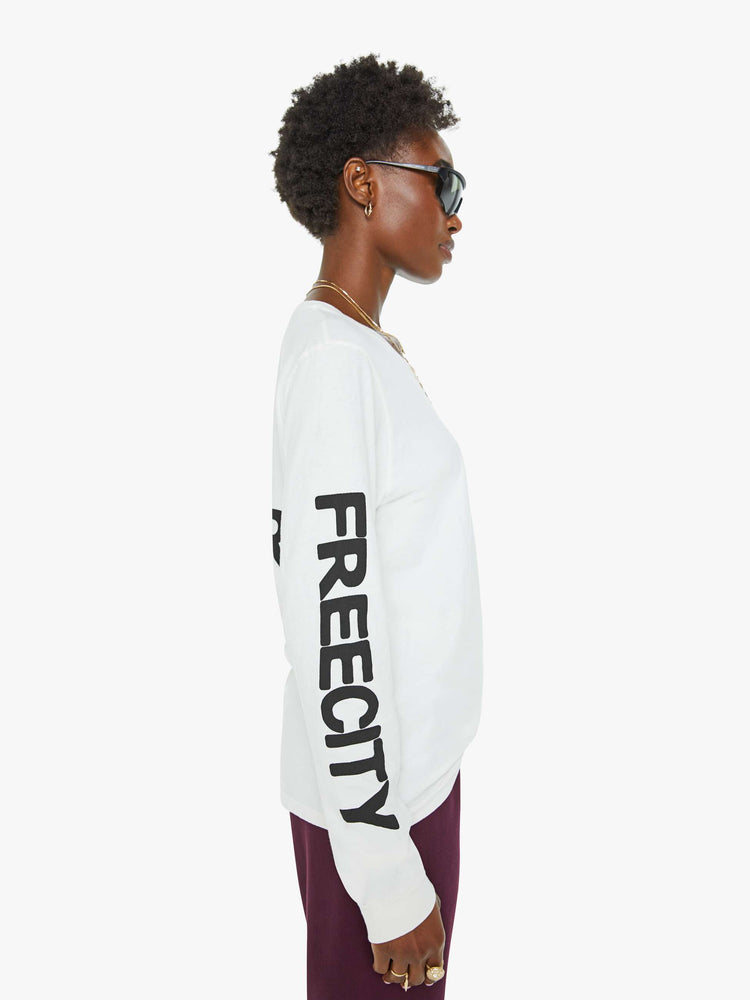 Side view of a woman long sleeve tee designed with ribbed hems, an oversized fit, a white bird on the chest and a text graphic on the back.