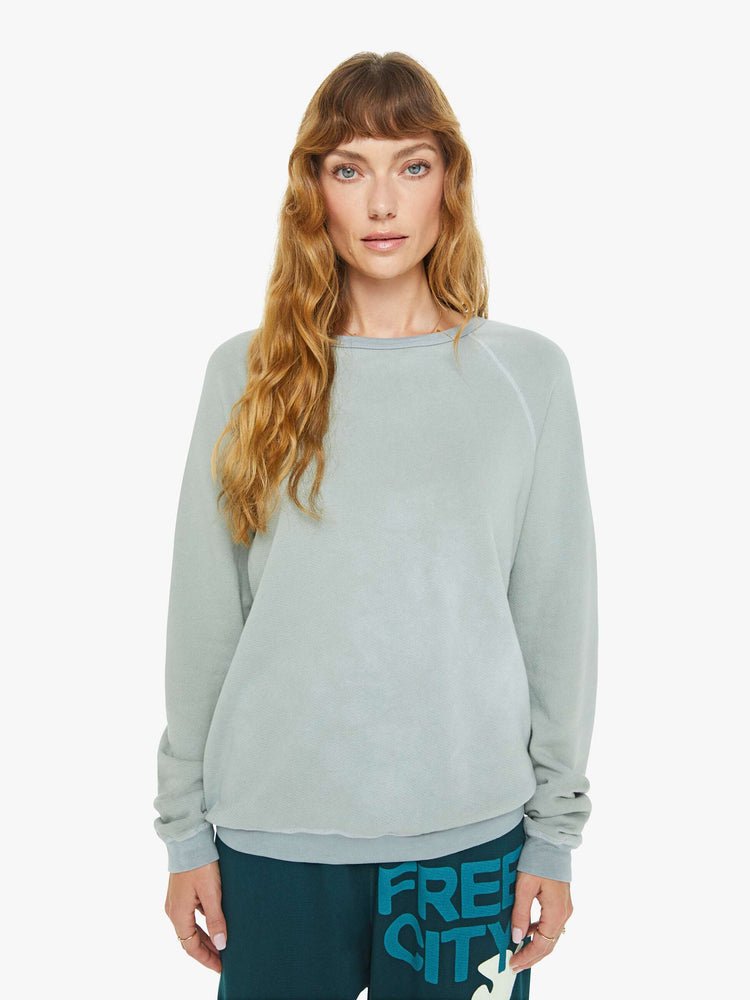 Front view of a woman in a in a light sky blue raglan sweatshirt designed with ribbed hems and an oversized fit.