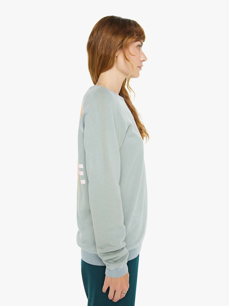 Side view of a woman in a in a light sky blue raglan sweatshirt designed with ribbed hems and an oversized fit.