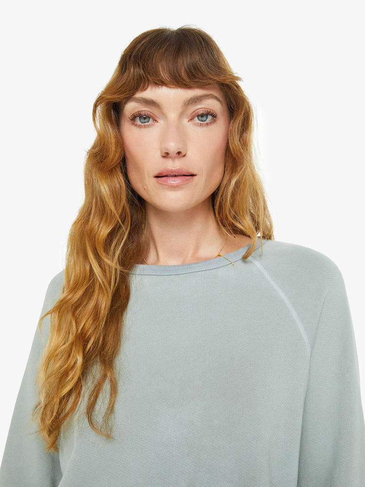 Close up view of a woman in a in a light sky blue raglan sweatshirt designed with ribbed hems and an oversized fit.