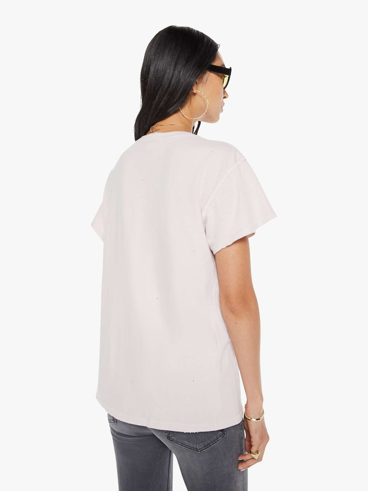 Back view of a woman in a distressed crewneck tee in faded baby pink, the tee pays homage to Willie Nelson with a graphic portrait on the front.