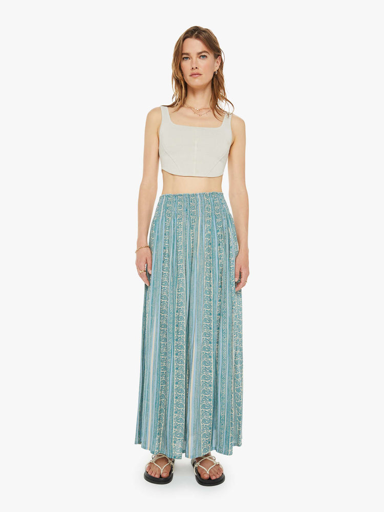 Front view of a woman maxi skirt in a teal stripe pattern, the skirt has a smocked waistband and a loose, flowy fit.