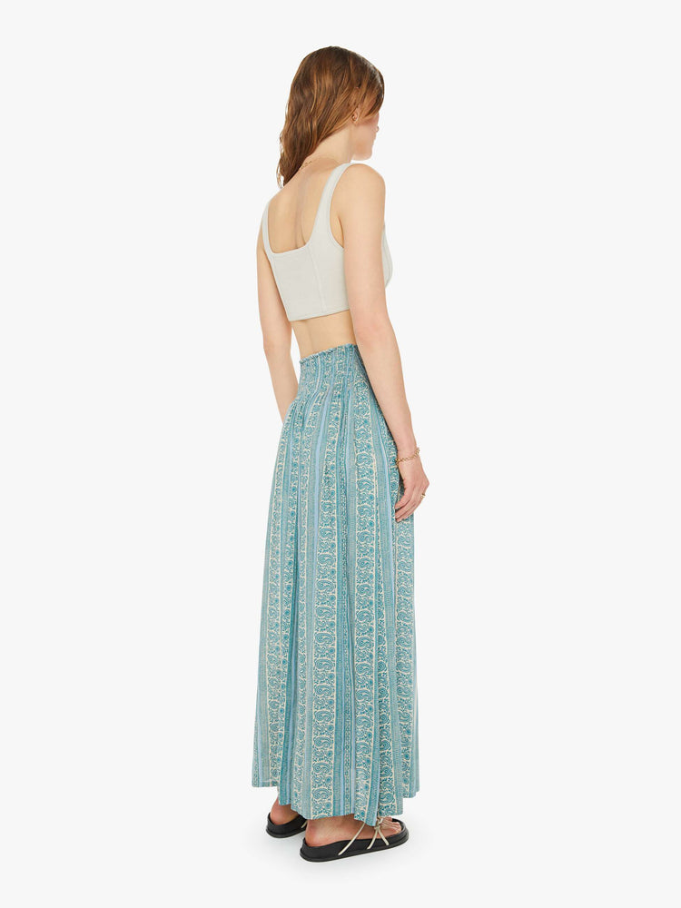 Back view of a woman maxi skirt in a teal stripe pattern, the skirt has a smocked waistband and a loose, flowy fit.