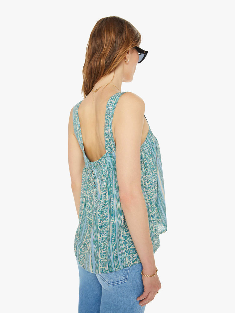 Back view of woman in a teal stripe pattern with detailed straps and buttons in the back.