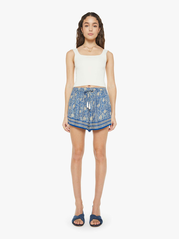 Front view of a woman in floral blue shorts are designed with an elastic high waist, side slit pockets, a slightly curved hem and a loose, flowy fit.