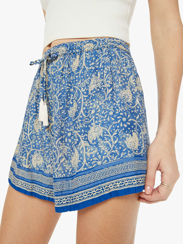 Close up view of a woman in floral blue shorts are designed with an elastic high waist, side slit pockets, a slightly curved hem and a loose, flowy fit.