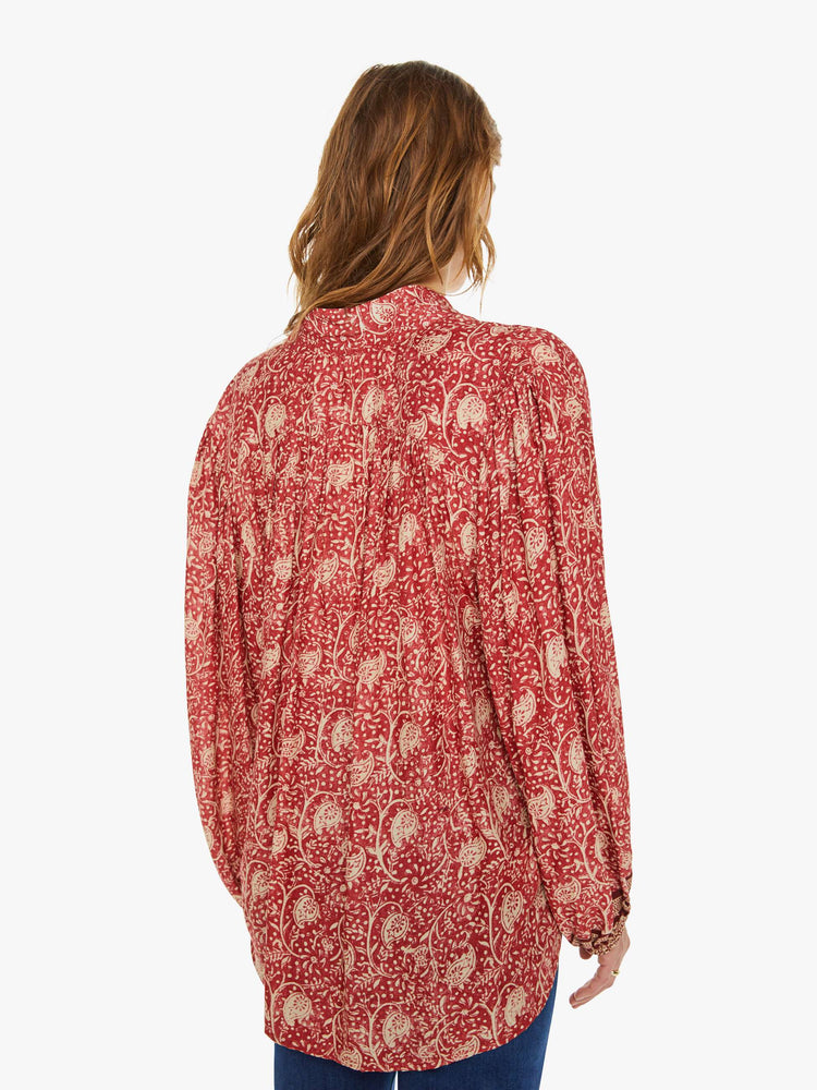 Back view of a woman in a floral blouse with buttoned V-neck, long balloon sleeves and a loose, flowy fit.