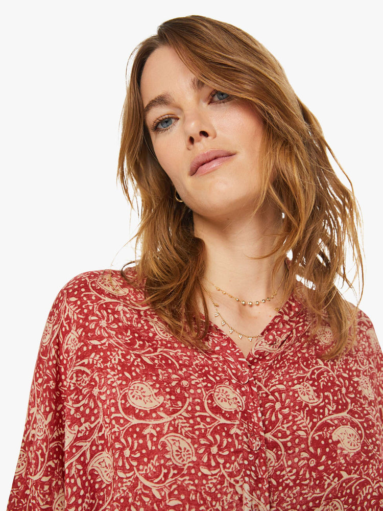 Close up view of a woman in a floral blouse with buttoned V-neck, long balloon sleeves and a loose, flowy fit.