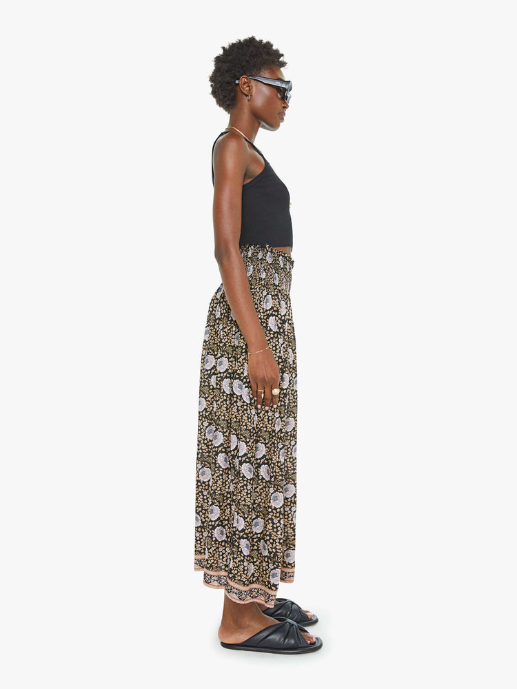 Side view of a black floral print maxi shirt with a smocked waistband and a loose, flowy fit.