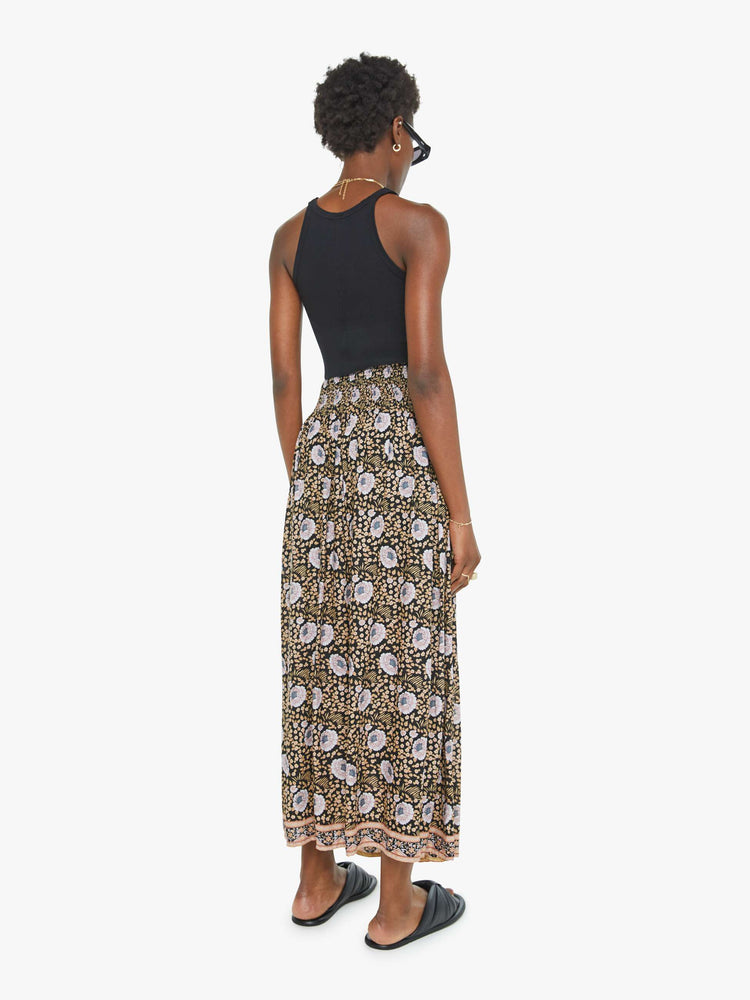 Back view of a black floral print maxi shirt with a smocked waistband and a loose, flowy fit.