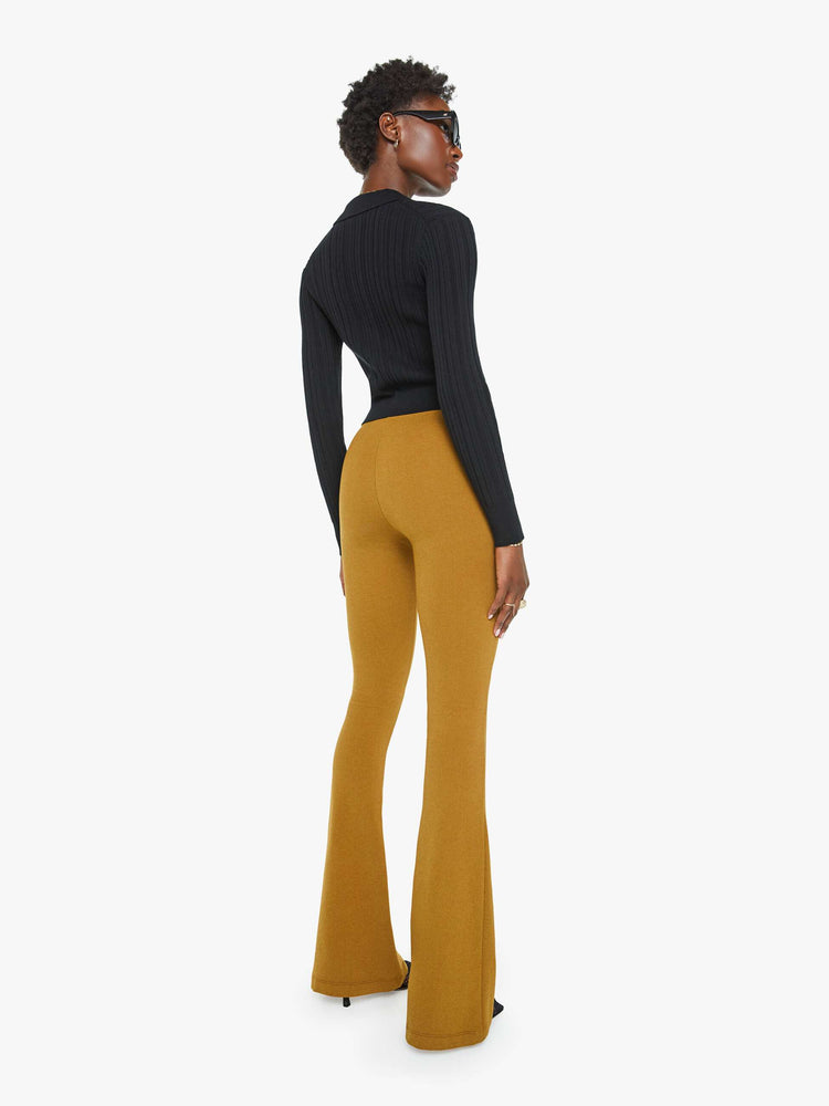 Back view of a woman in gold brown pant with a high rise, flared leg, elastic waistband and pintuck details down the front.