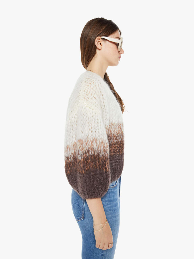 Side view of a woman hand-knit cardigan  with drop shoulders and bracelet-length balloon sleeves in brown, cream and white ombre design.