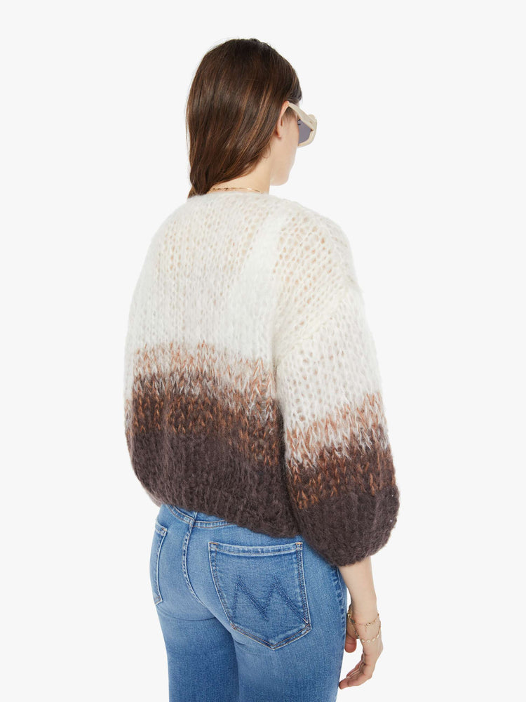 Back view of a woman hand-knit cardigan  with drop shoulders and bracelet-length balloon sleeves in brown, cream and white ombre design.