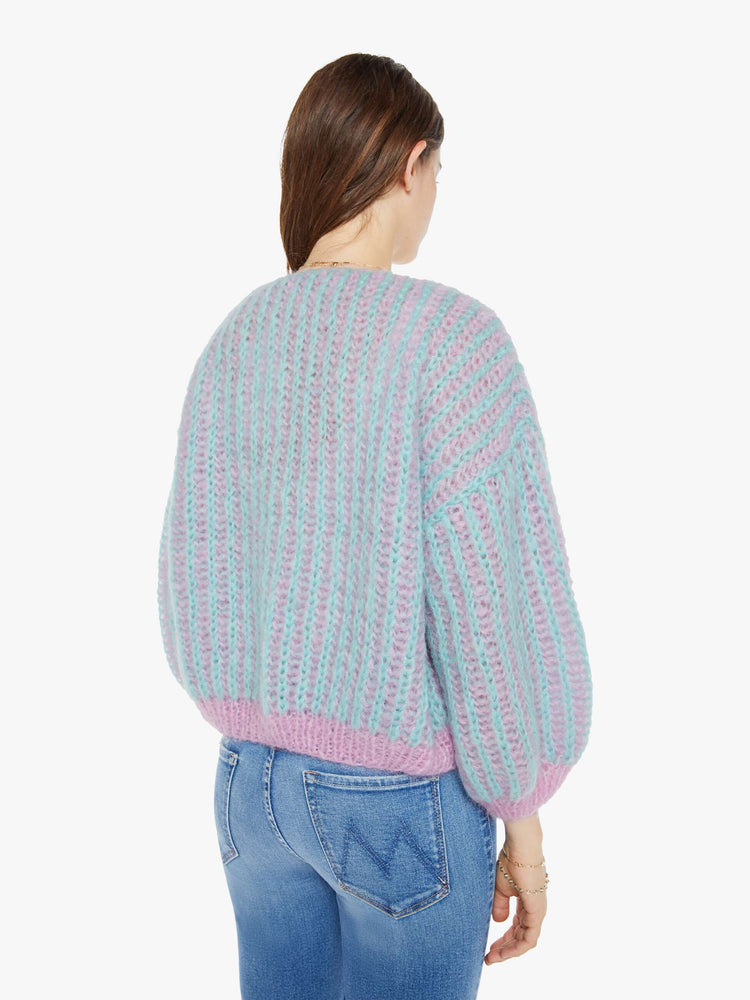 Back view of a woman in a hand knit cardigan with drop shoulders and bracelet-length balloon sleeves in rose and mint color.