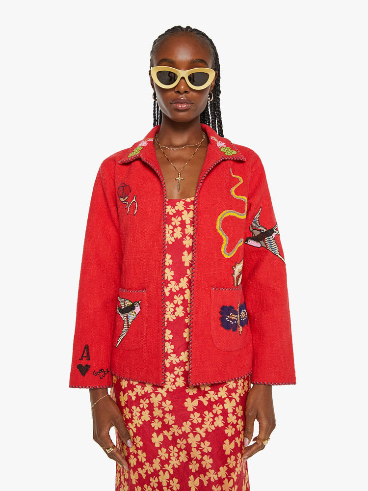 Front view of a woman in a red jacket with beaded motifs and dropped shoulders, front patch pockets and a tailored fit that hugs the body like a blazer.