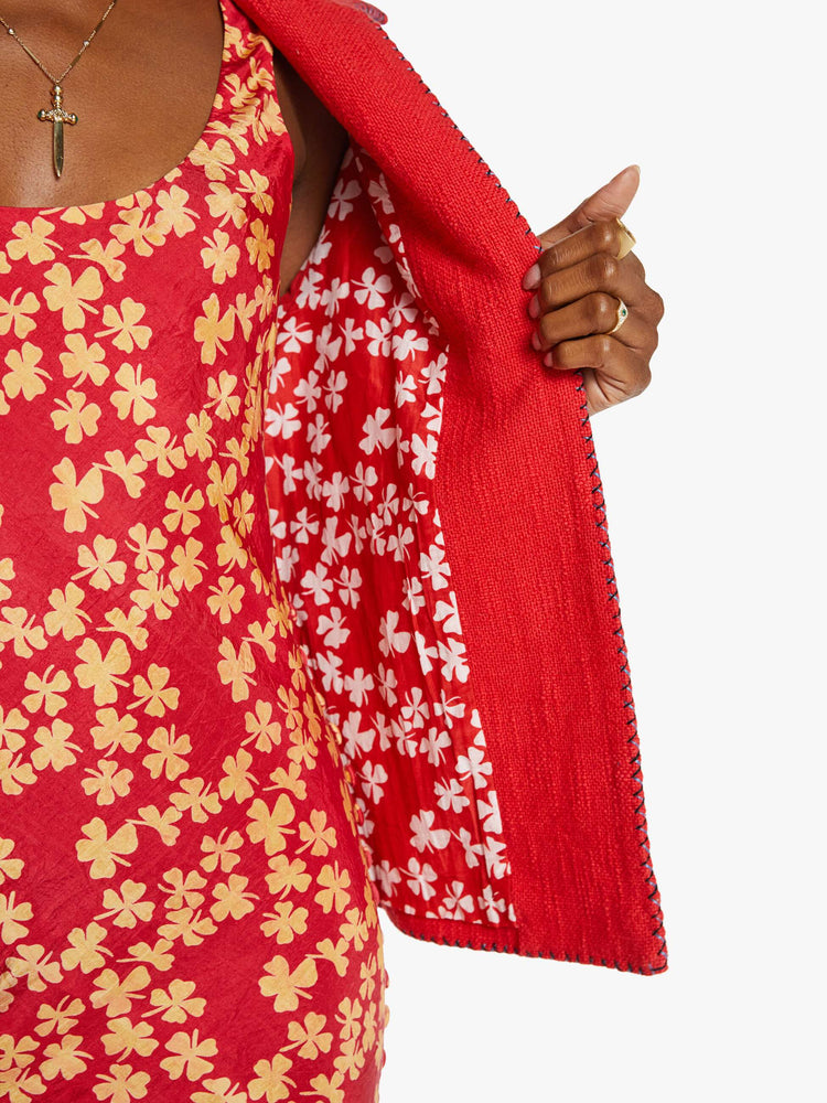 Close up view of a woman in a red jacket with beaded motifs and dropped shoulders, front patch pockets and a tailored fit that hugs the body like a blazer.