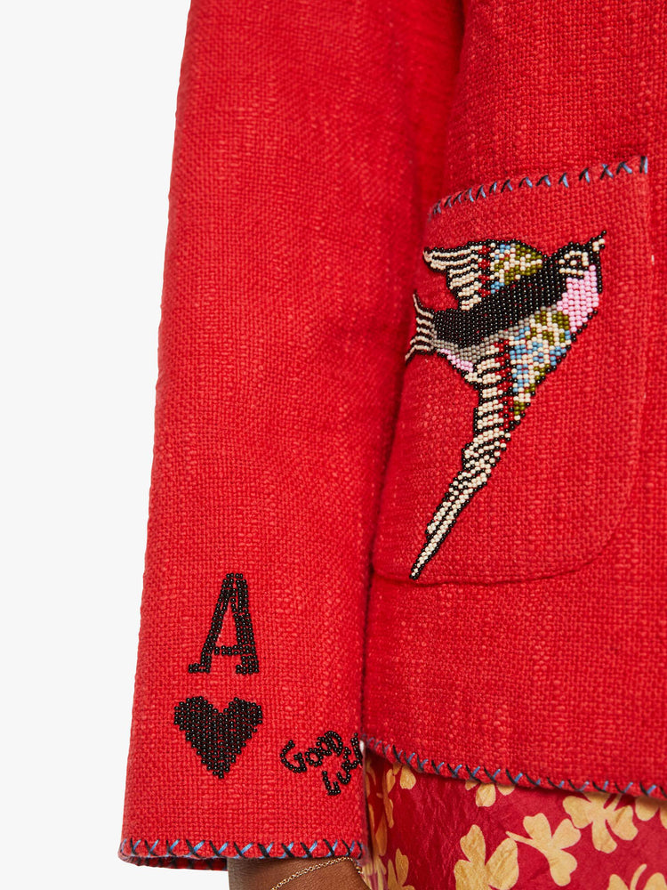 Swatch view of a woman in a red jacket with beaded motifs and dropped shoulders, front patch pockets and a tailored fit that hugs the body like a blazer.