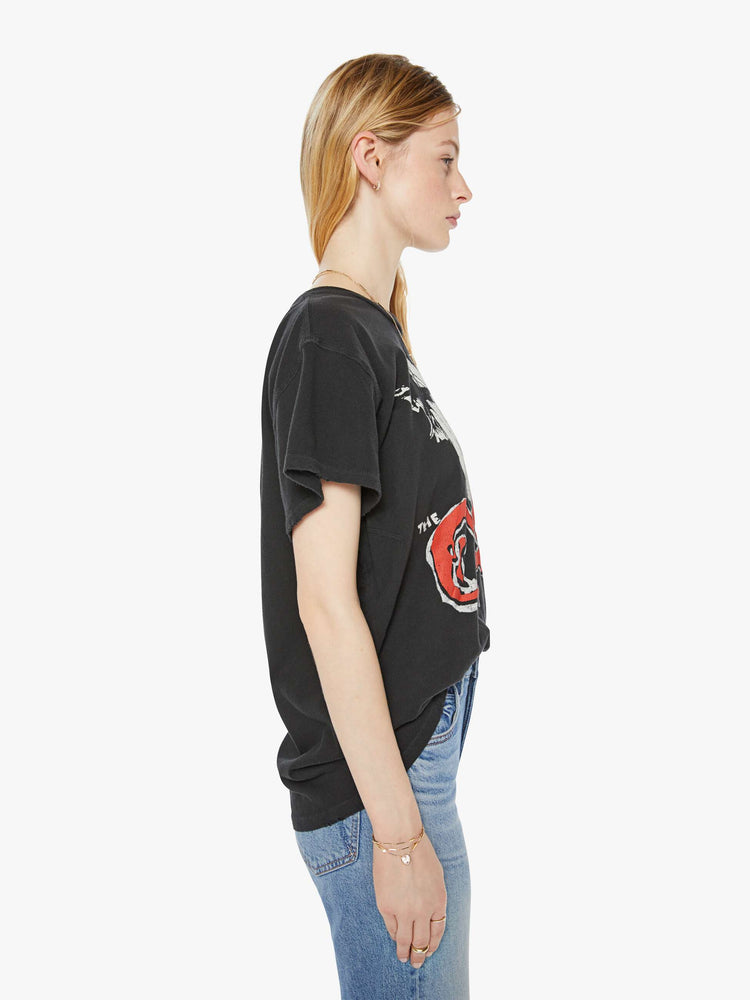 WOMAN side view of a woman in a black tee that pays homage to The Cure with a graphic portrait and text in red on the front.