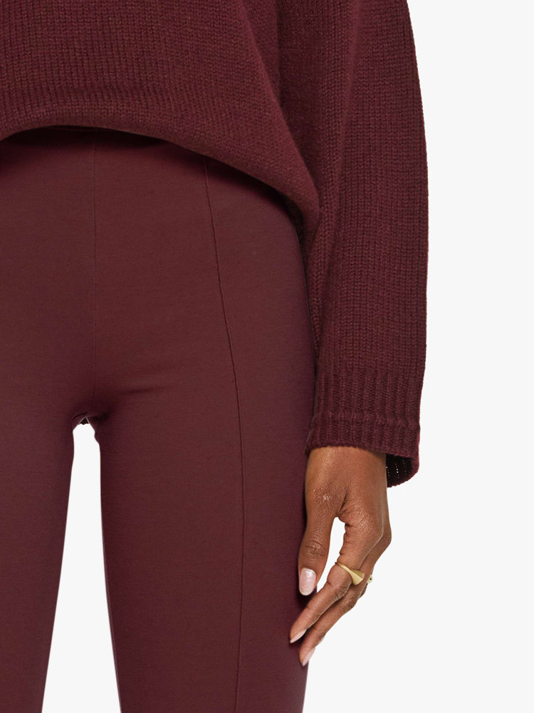 Close up view of a woman in a rich  red pants designed with a high rise, flared leg, elastic waistband and pintuck details down the front.