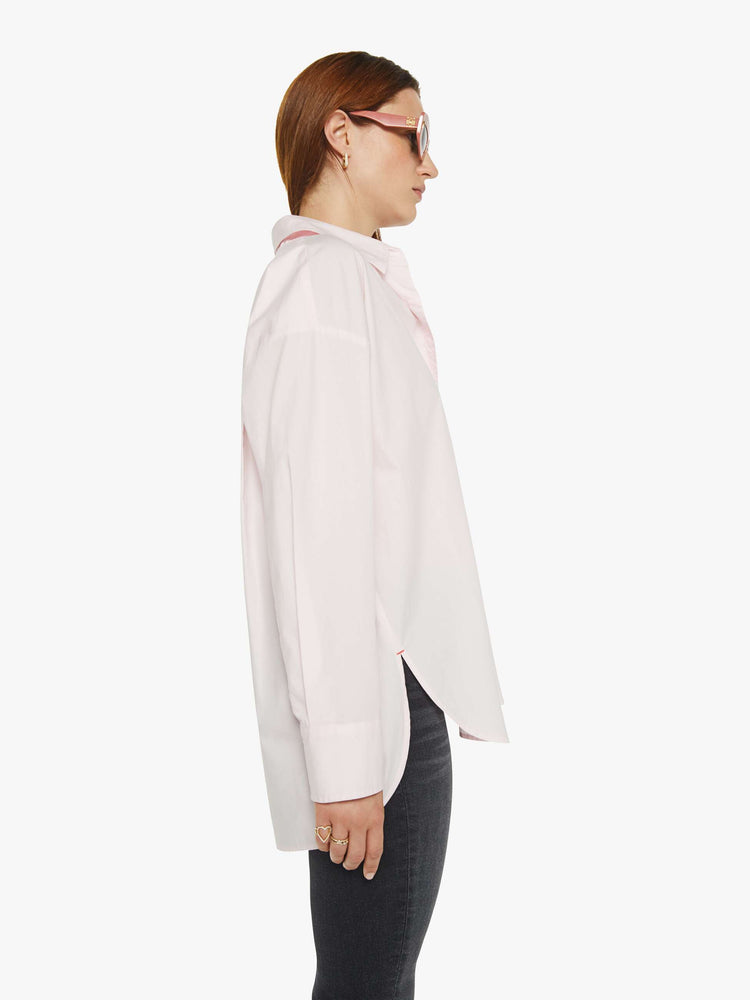 WOMAN side view of a woman in light pink oversized button-up blouse with drop shoulders, a front patch pocket, curved hem and a loose fit.