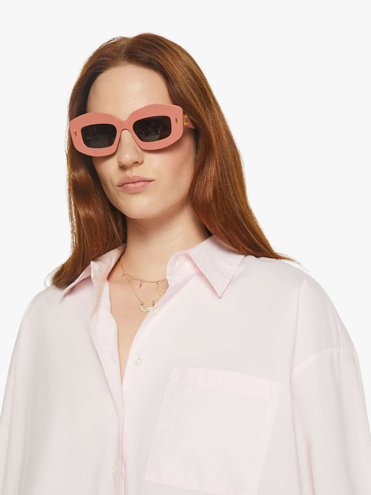 WOMAN close up  view of a woman in light pink oversized button-up blouse with drop shoulders, a front patch pocket, curved hem and a loose fit.