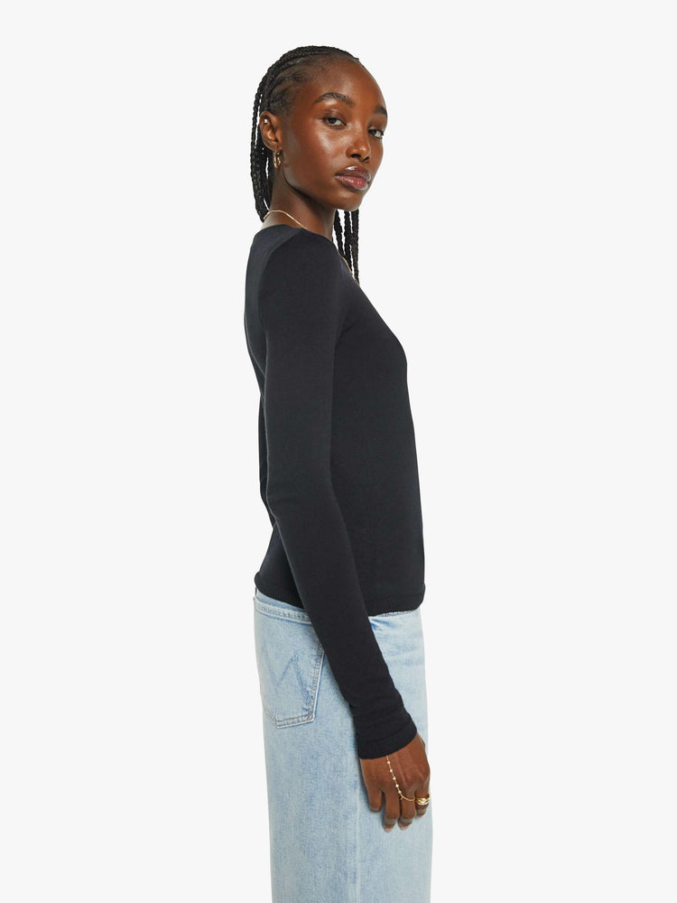 Side view of a womans in a long sleeve sweater in black with a high crew neck and a narrow fit.