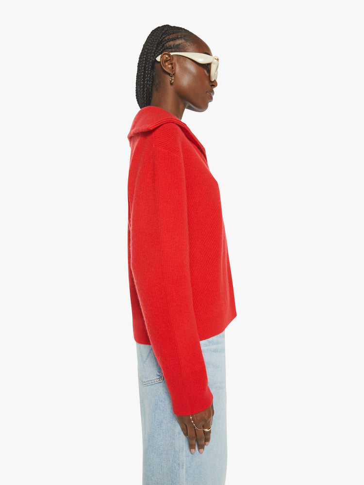 WOMAN Side view of a woman in a red sweater with a V-neck that zips, drop shoulders and a loose fit.