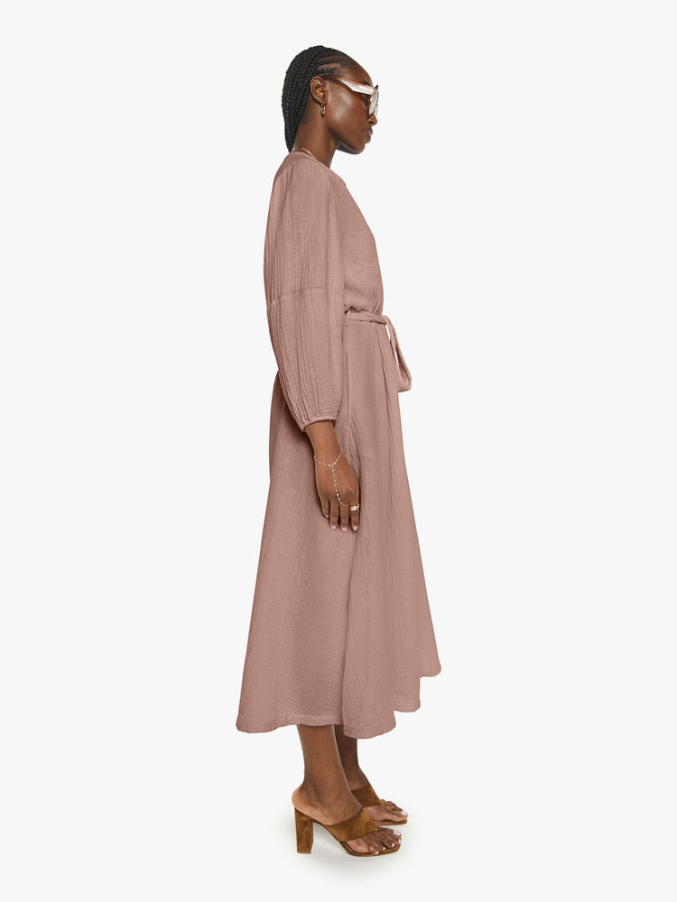 Side view of a woman in a dusty rose vneck button down the front and loose dress.